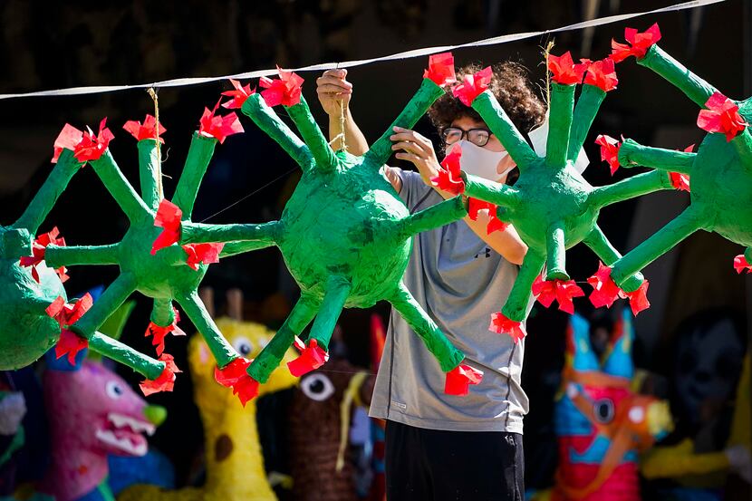 Carlos Sagero hangs a coronavirus piñata on a line after putting the finishing touches of...