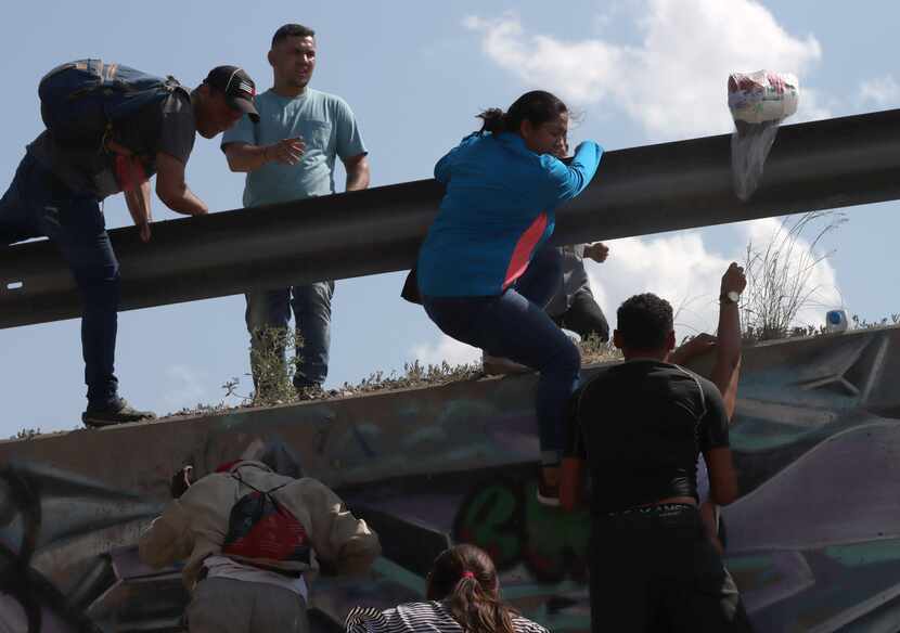 Men and women jump a barrier in Ciudad Juárez, on the Mexican side of the Rio Grande, in...