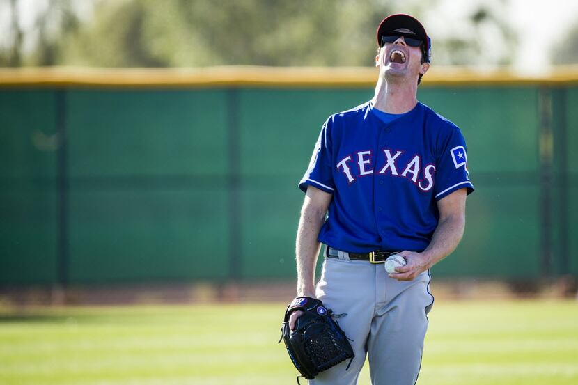Texas Rangers pitcher Cole Hamels (35) laughs while playing catch with Martin Perez during a...