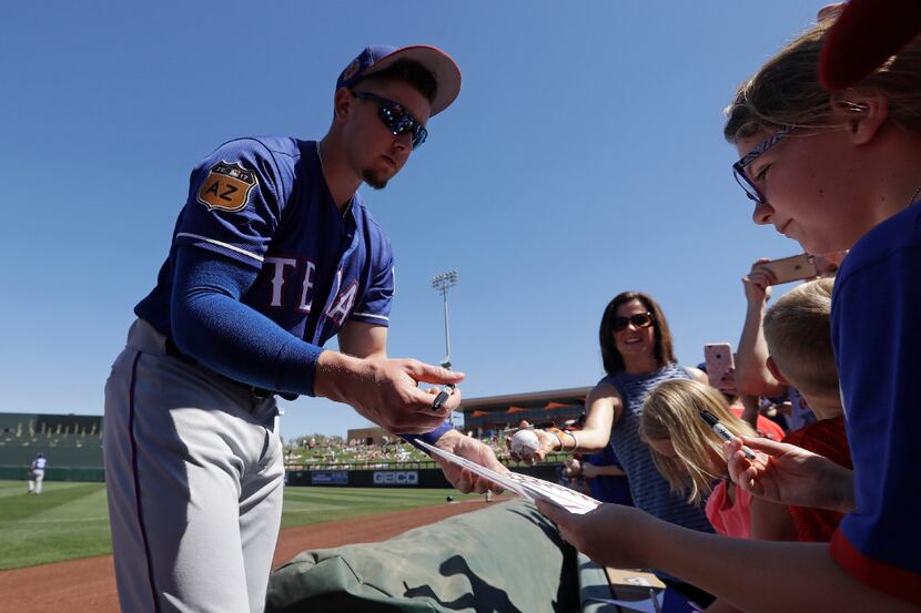 Texas Rangers' Ryan Rua gives autographs before a spring training baseball game against the...