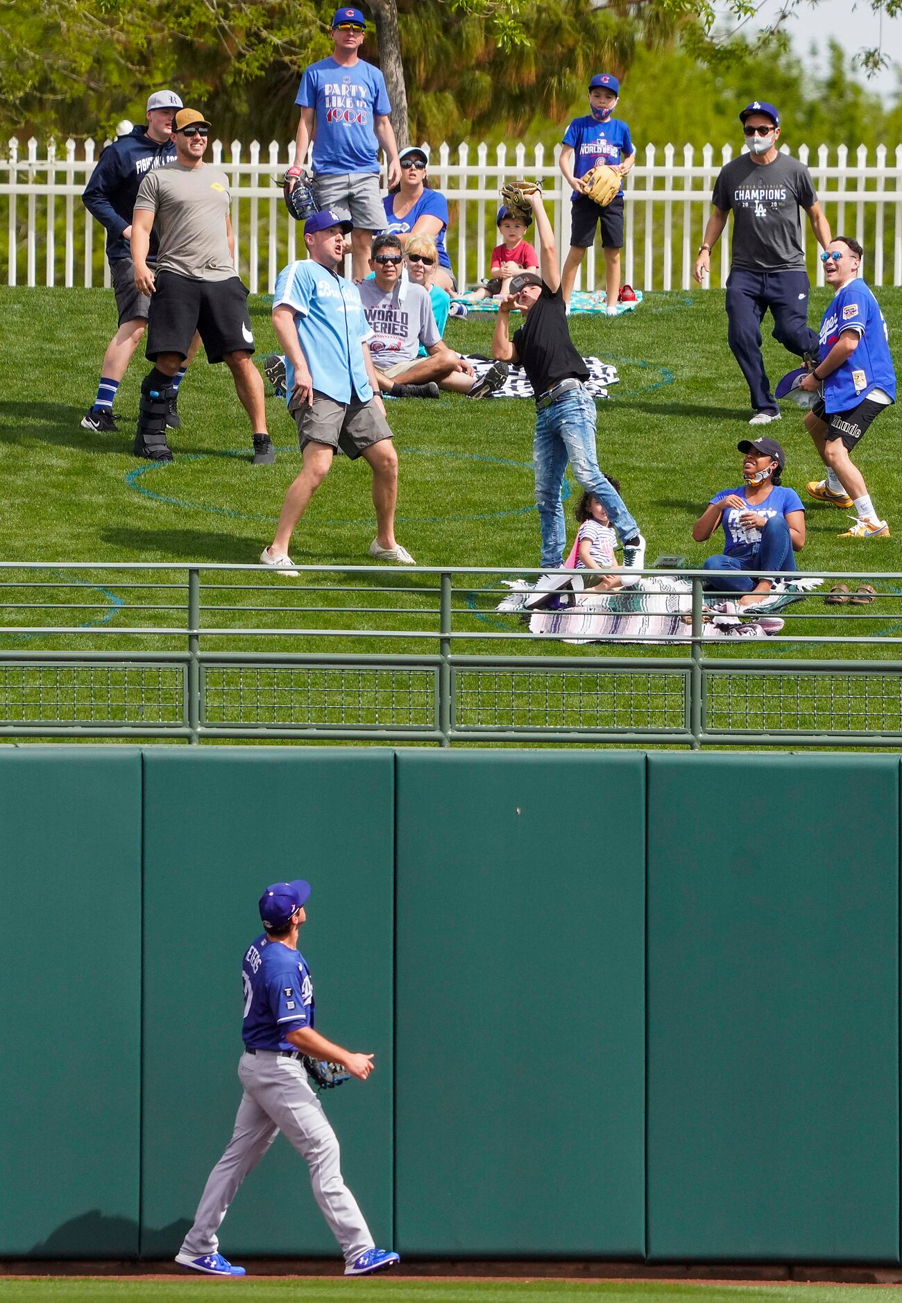 A fan makes a catch as Los Angeles Dodgers center fielder DJ Peters watches a solo home run...