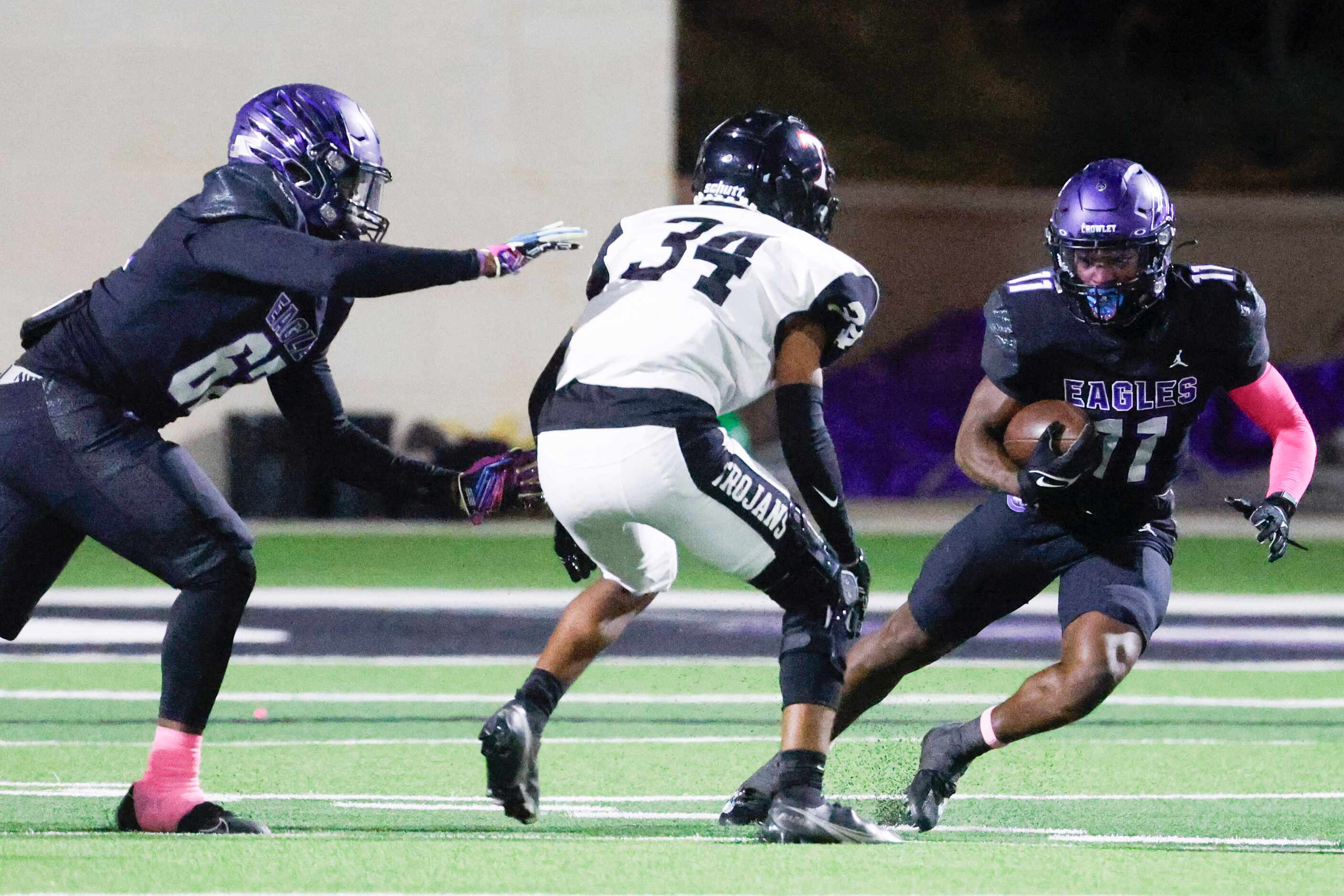 Crowley High’s Curtis Johnson (11) runs with the ball past Trinity High’s Troy Michele (34)...