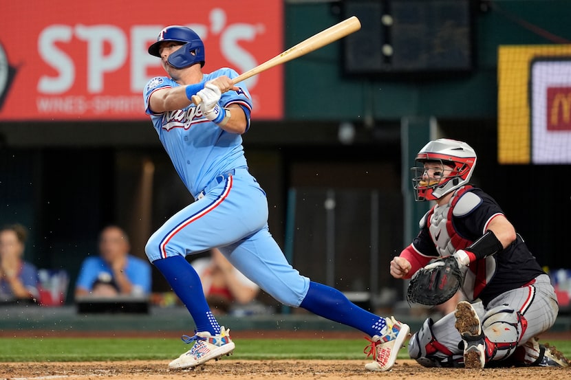 Texas Rangers' Josh Jung, left, follows through on a single that allowed Adolis Garcia to...