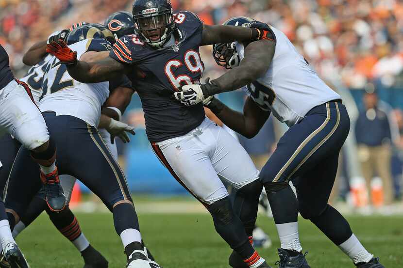 Henry Melton #69 of the Chicago Bears rushes past Harvey Dahl #62 (L) and Barry Richardson...