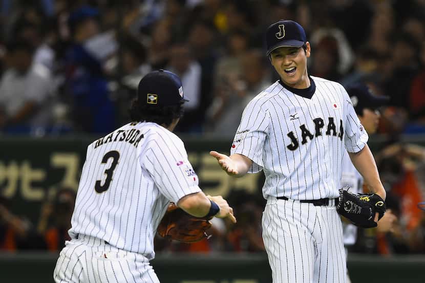 TOKYO, JAPAN - NOVEMBER 19:  Starting pitcher Shohei Otani (R) #16 of Japan high fives with...