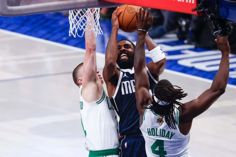 Dallas Mavericks guard Kyrie Irving (center) drives to the basket against Boston Celtics...