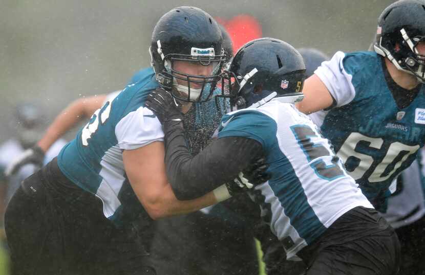 Rain splashes off of Luke Joeckel, left, as he pushes and shoves with Ryan Davis (59) during...