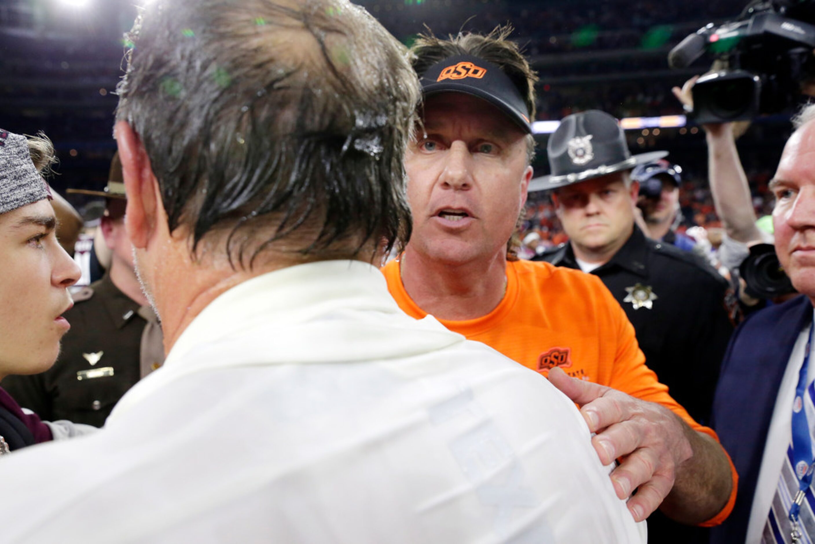 Texas A&M coach Jimbo Fisher, foreground, and Oklahoma State coach Mike Gundy, right, meet...