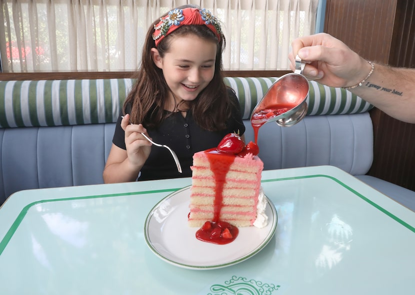 Adelaide Hoffman, 8, watches as strawberry sauce is poured on the Big Pink Cake at...