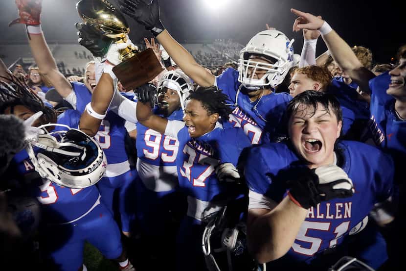 Allen football players celebrate with the winning trophy after defeating Arlington Martin in...