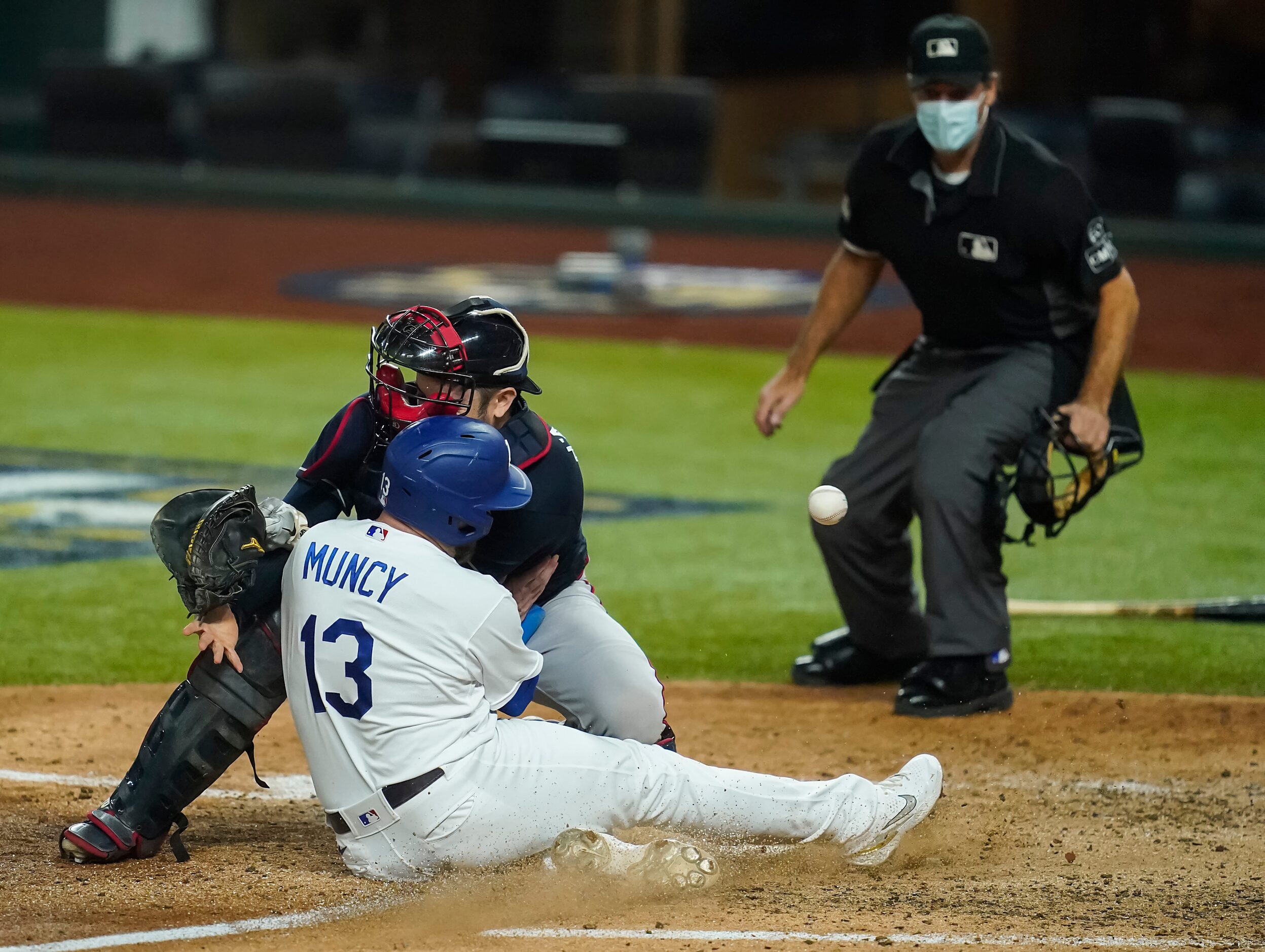 Los Angeles Dodgers first baseman Max Muncy scores past Atlanta Braves catcher Travis...