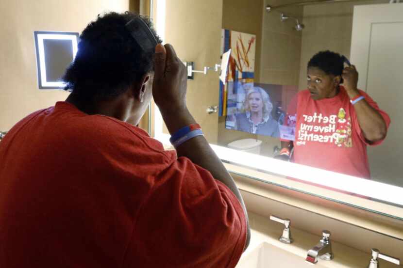 Carol 'Mama' Hawkins, 58, combs her hair in a mirror that has a built-in TV in the bathroom...