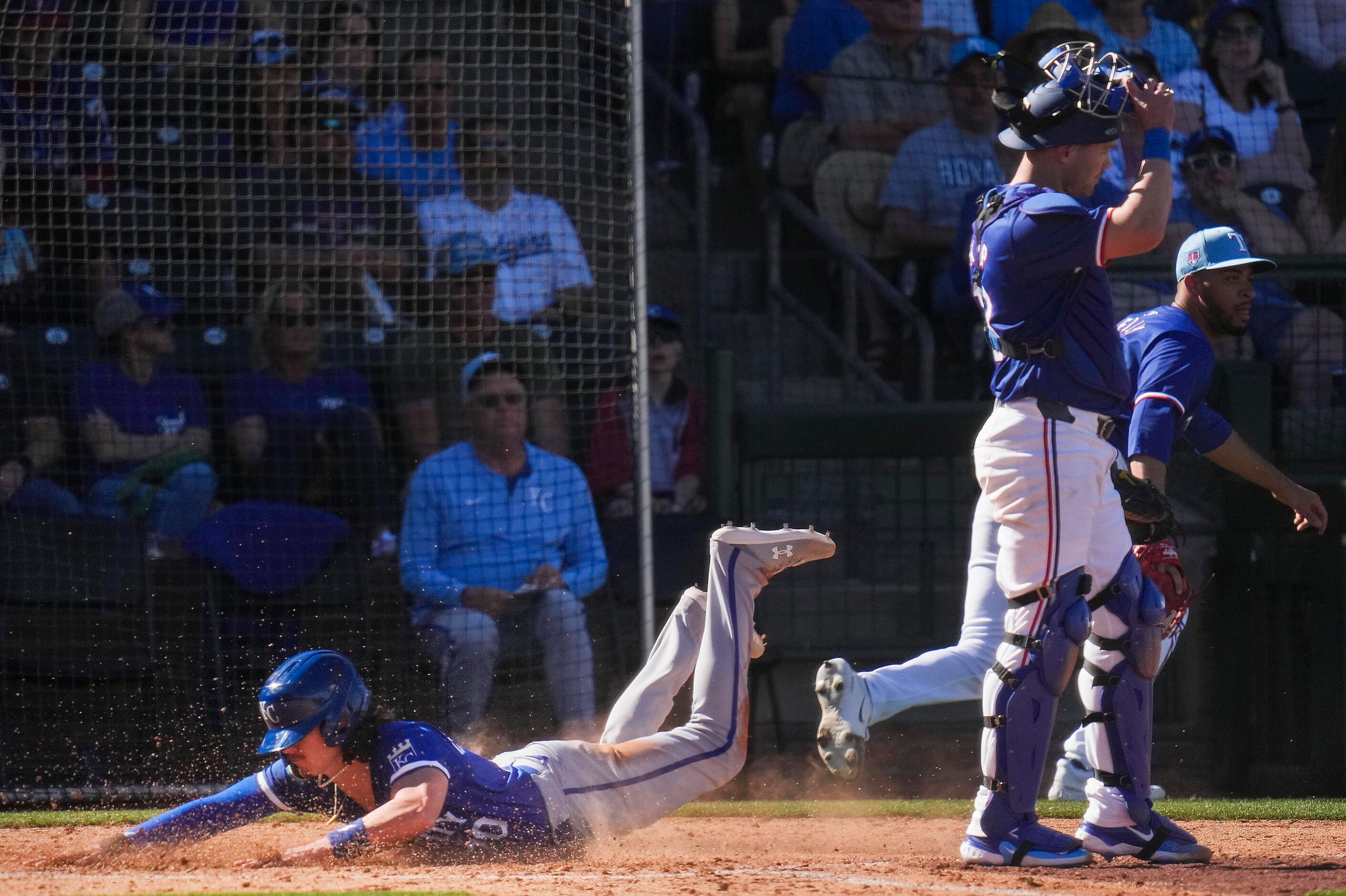 Carter Jensen of the Kansas City Royals scores past Texas Rangers catcher Andrew Knapp and...