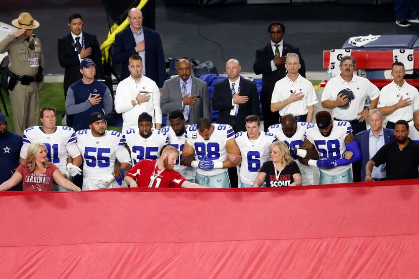 Dallas Cowboys link arm in arm during the National Anthem prior to the start of a game...