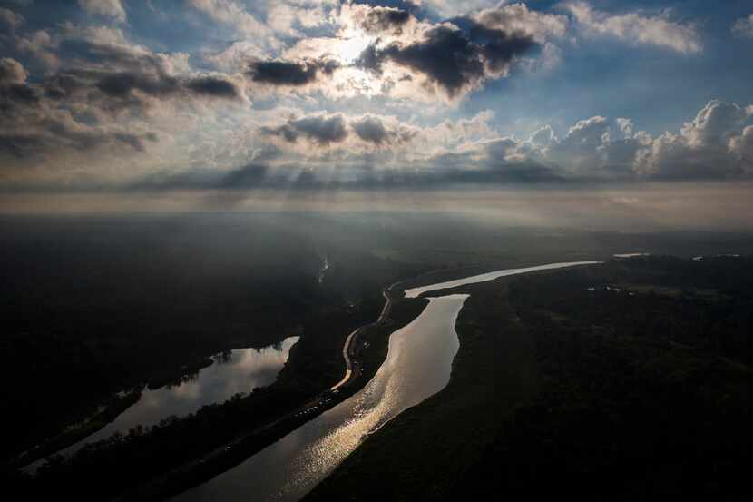 The Trinity River reflects the sun through the clouds over the Great Trinity Forest, on...