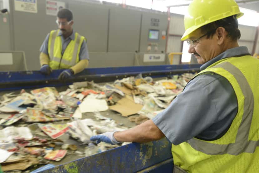 Alfredo Salgado (right) sorts paper, plastic and metal at Republic Services’ new recycling...