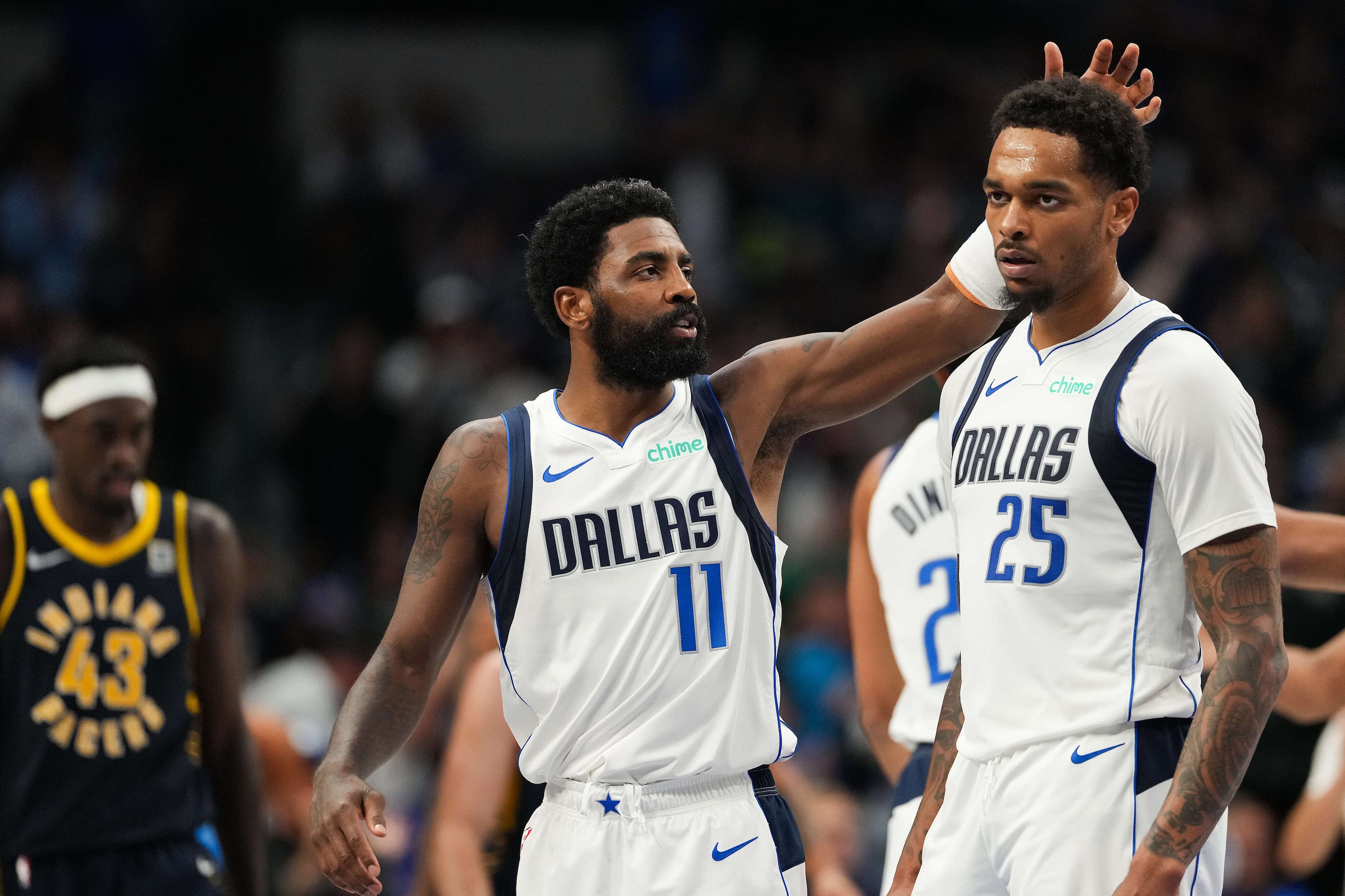 Dallas Mavericks forward P.J. Washington (25) gets a pat on the head from guard Kyrie Irving...