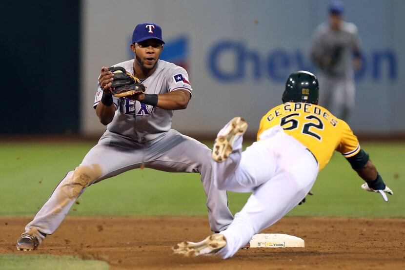 Texas shortstop Elvis Andrus gets set to tag Oakland's Yoenis Cespedes who was picked off...