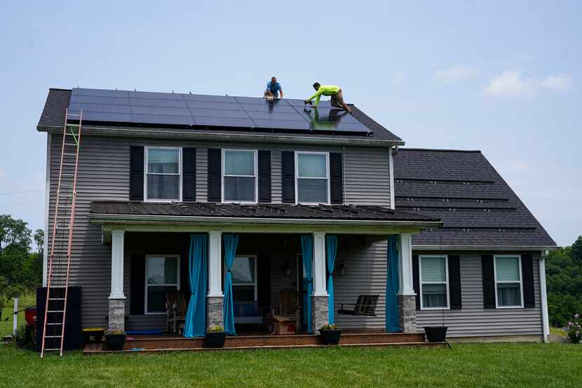 Workers install solar panels on the roof of a home in Kentucky.