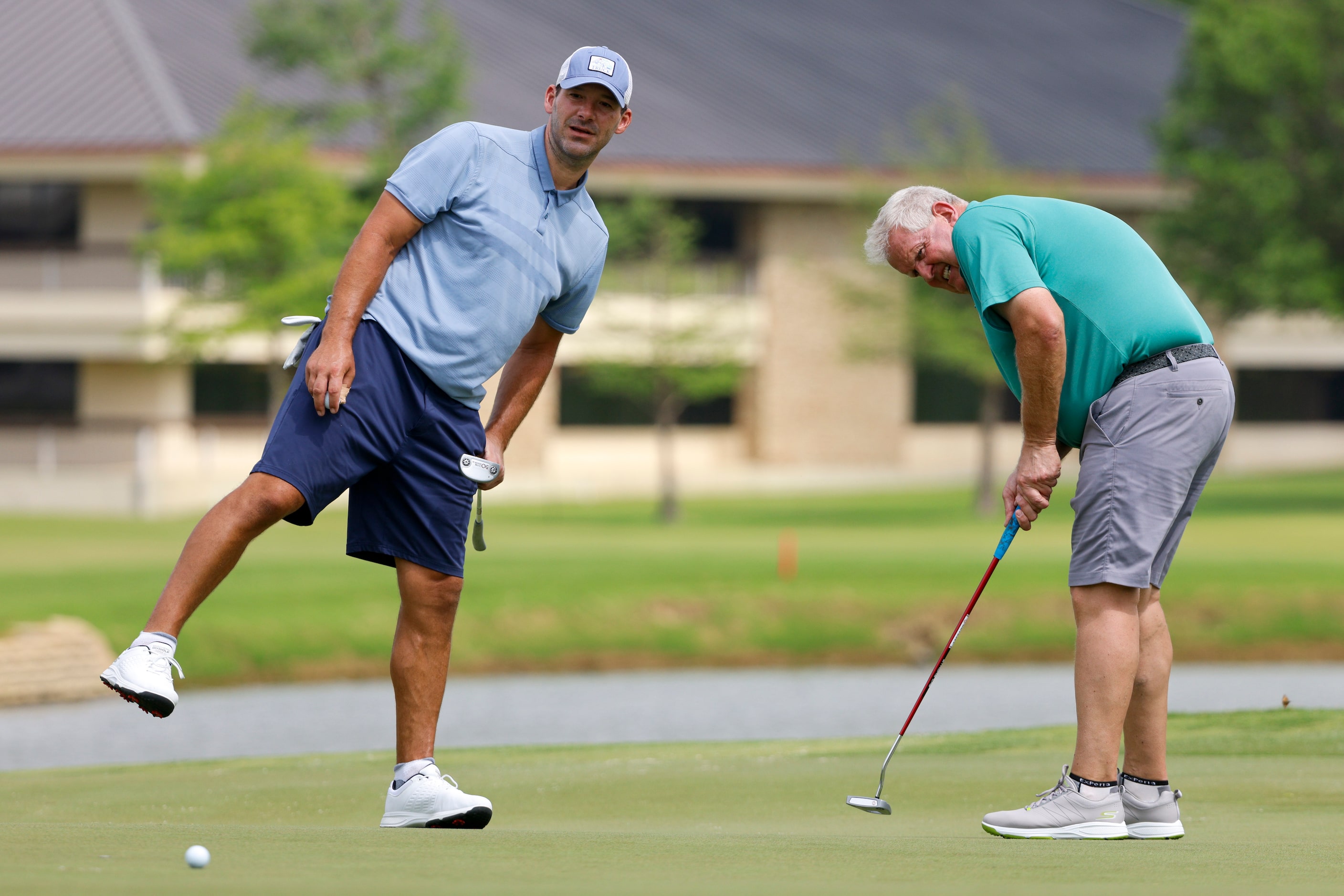 Former Dallas Cowboys quarterback Tony Romo (left) leans in to watch a putt by professional...