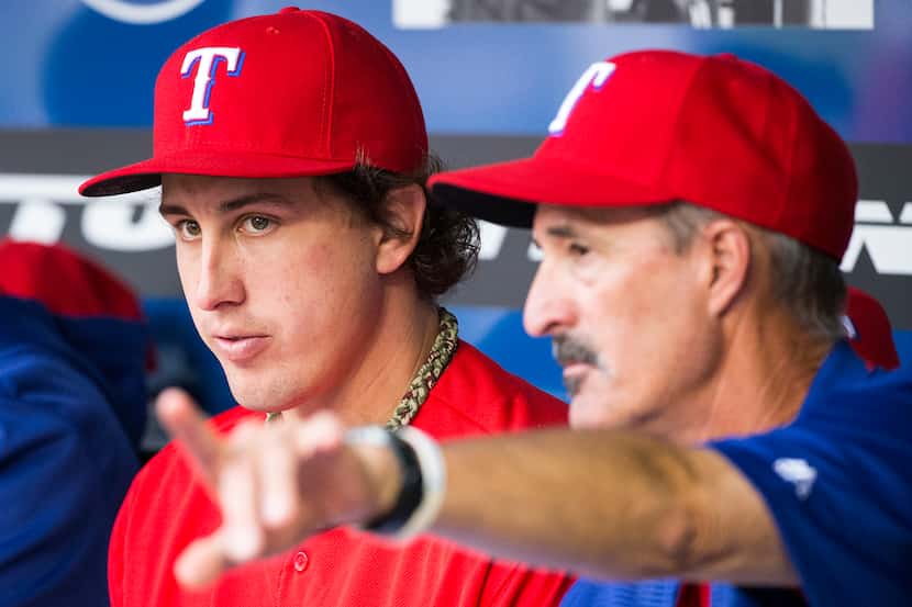 Texas Rangers starting pitcher Derek Holland talks with pitching coach Mike Maddux in the...