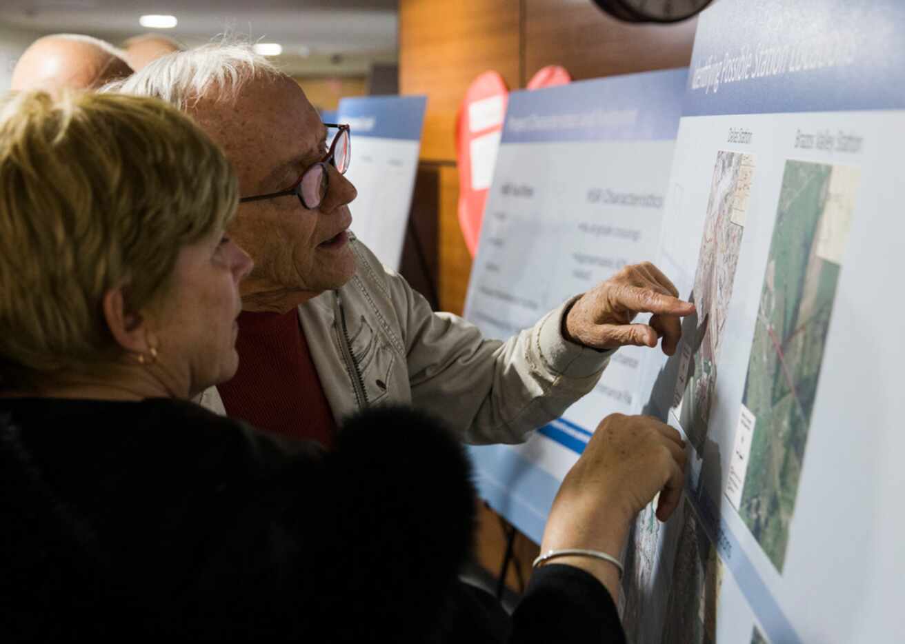 Susan Anderson and James Mannos look at maps of possible station locations during an open...
