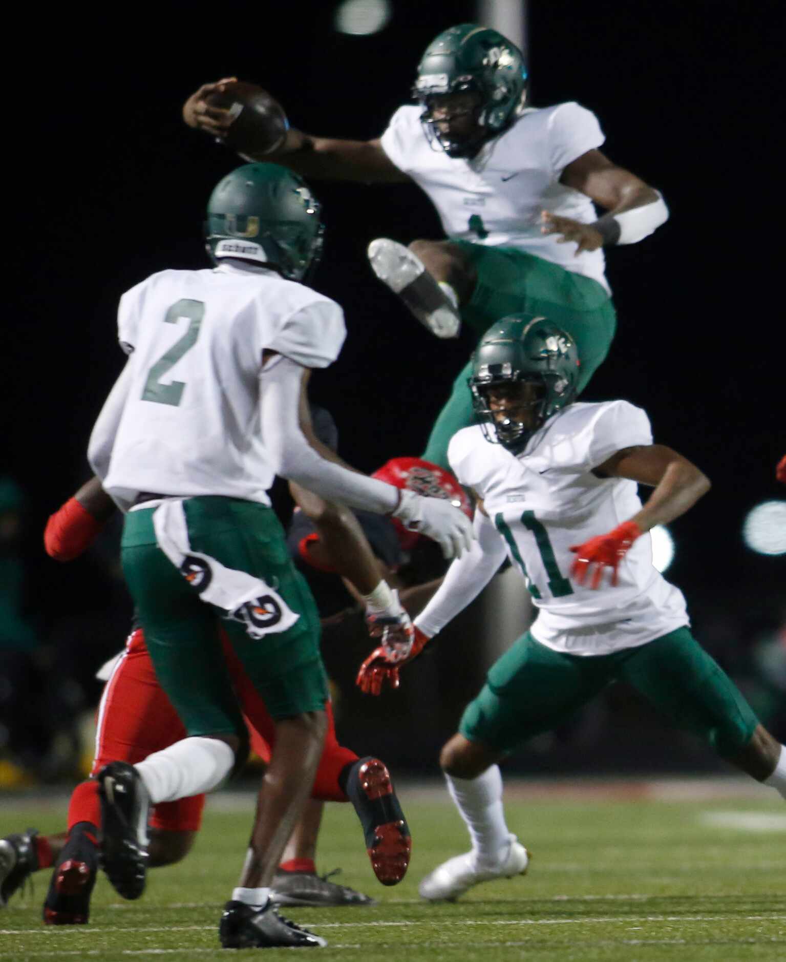 DeSoto quarterback Samari Collier (1) attempts to leap over a Cedar Hill defender as he...