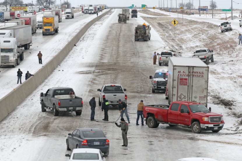 A Texas Department of Transportation truck spread gravel along an icy stretch of I-35 in...