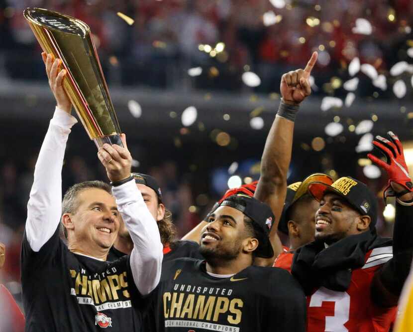 Ohio State head coach Urban Meyer hoists the national championship trophy as running back...