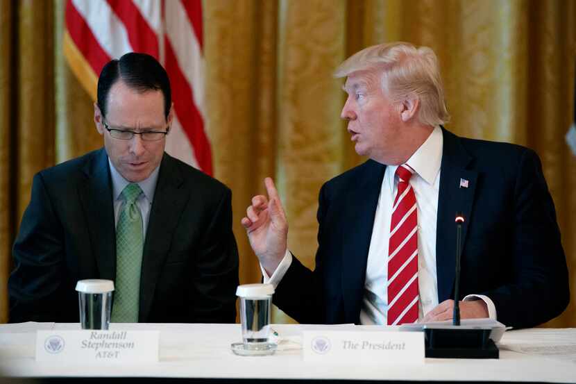 AT&T CEO Randall Stephenson, left, listens as President Donald Trump speaks during the...