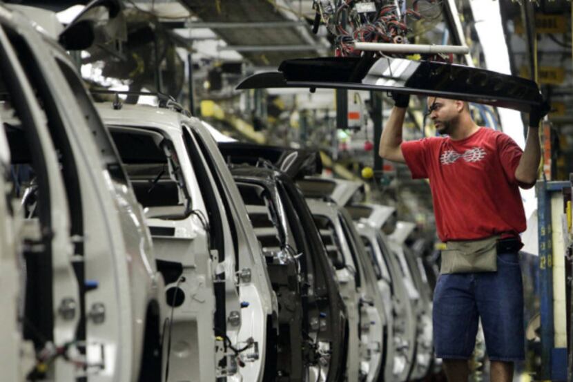 A rear window for a full-size SUV is swung into position at the GM assembly plant. GM will...