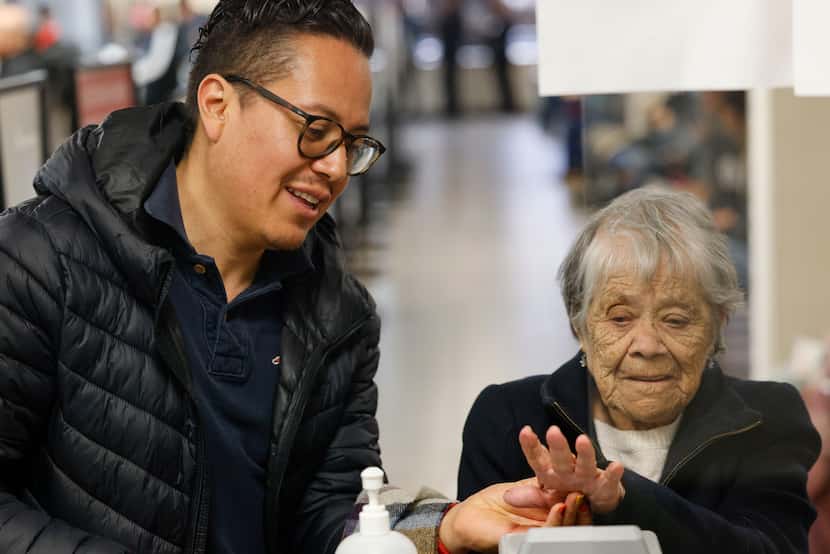 Damian Bautista (left), helps his grandmother Concepcion Trejo, 101, with her biometrics as...