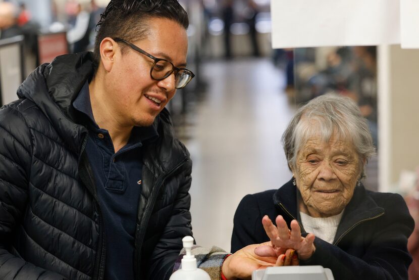 Damian Bautista (left), helps his grandmother Concepcion Trejo, 101, with her biometrics as...