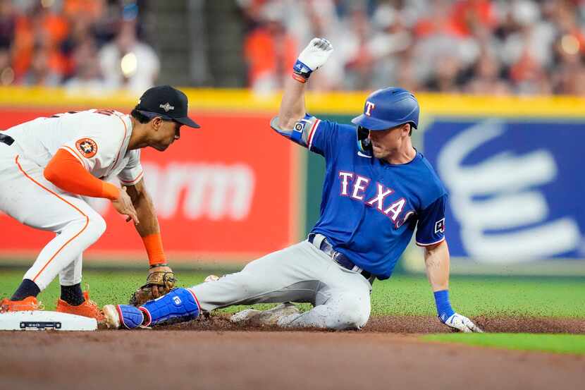 Texas Rangers left fielder Evan Carter (32) slides safely into second with a second inning...