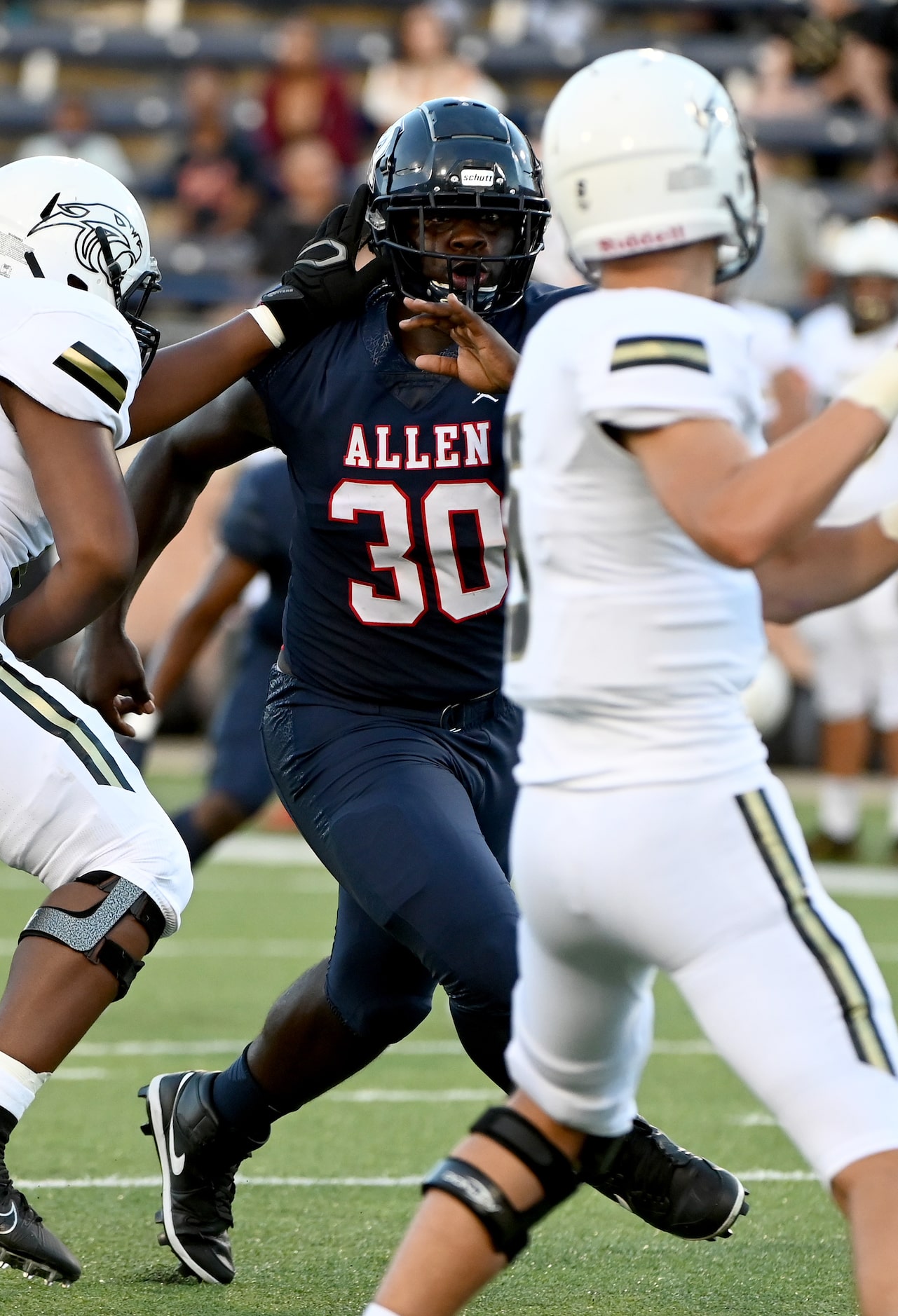 Allen’s DJ Hicks (30) fights through a block by Plano East’s Ralee Jackson as quarterback...