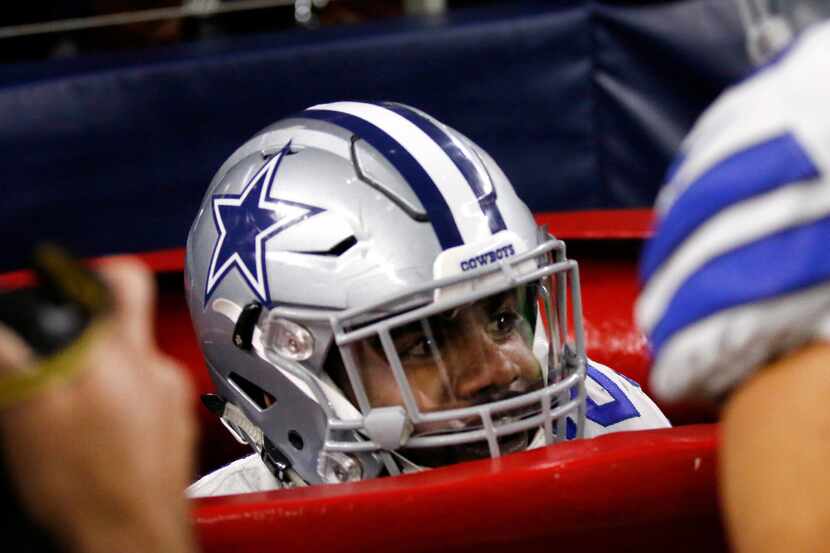 Dallas Cowboys running back Ezekiel Elliott peeks out of a large Salvation Army kettle after...