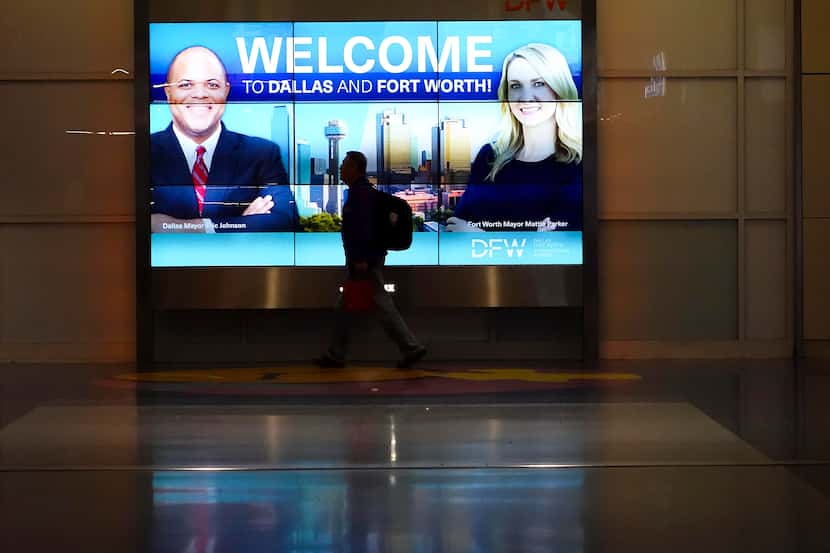 Passengers walk between gates of Terminal A past a display with images of Dallas mayor Eric...