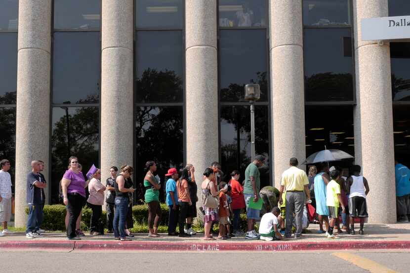 Parents and their children wait in line for their back to school vaccinations at the Dallas...