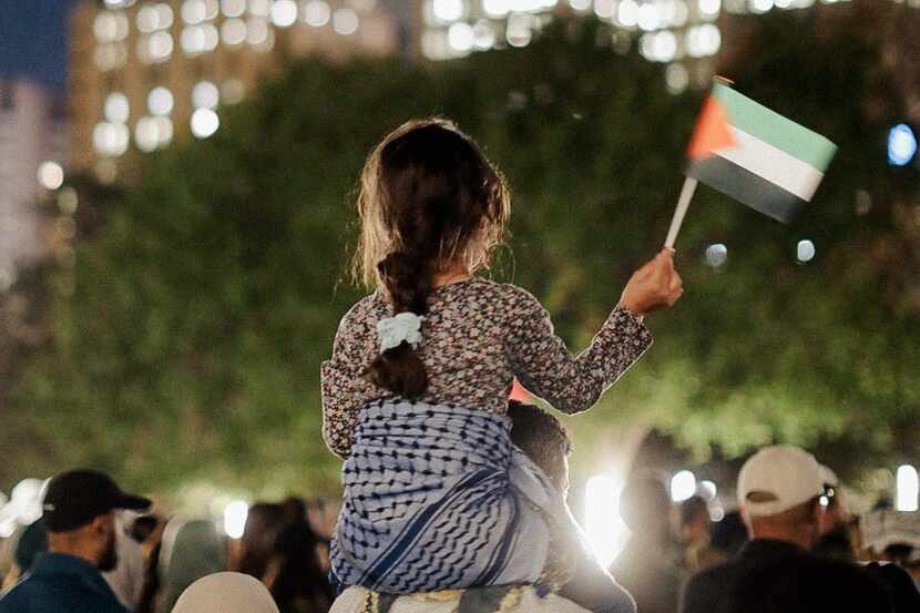 A child holds a Palestinian flag during a Wednesday night vigil at Dallas City Hall.
