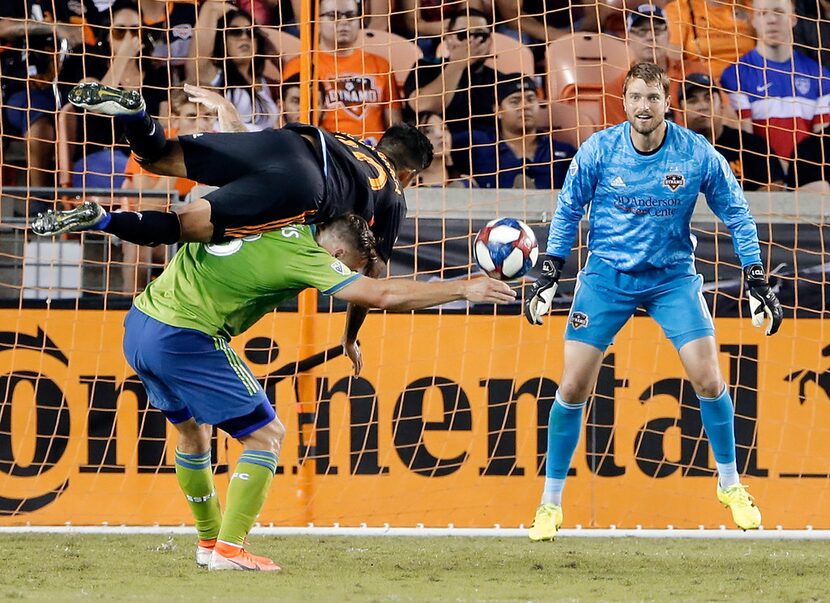 Houston Dynamo defender A. J. DeLaGarza, top, goes over Seattle Sounders forward Jordan...