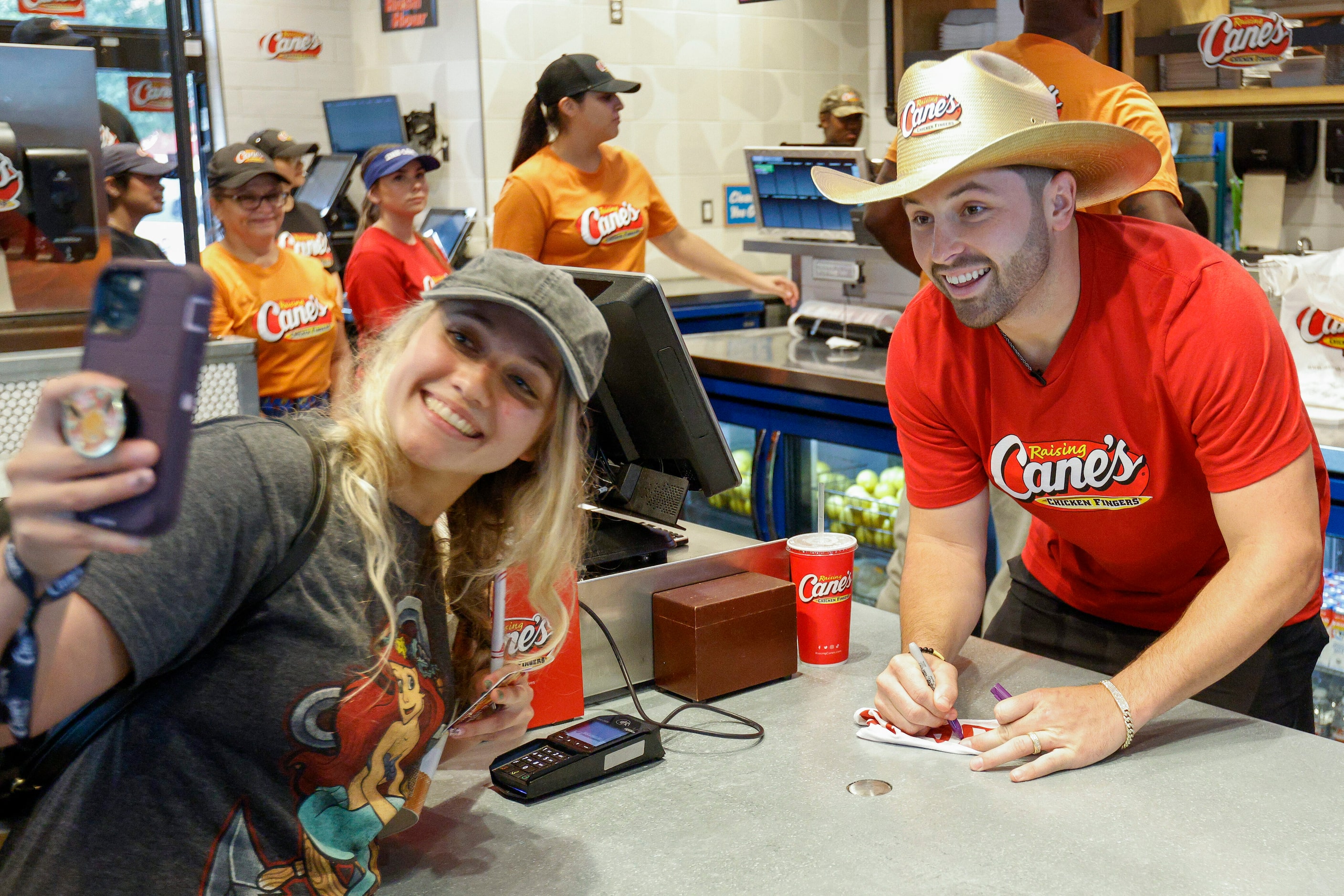 Arianna Lujano takes a selfie with former Oklahoma quarterback Baker Mayfield as he works...