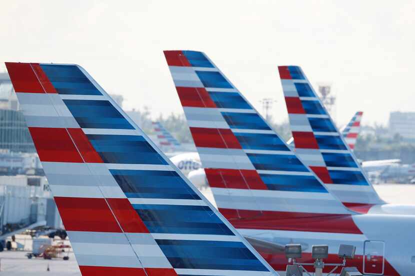 Painted vertical stabilizers are viewed as American Airlines jets are parked on the airport...
