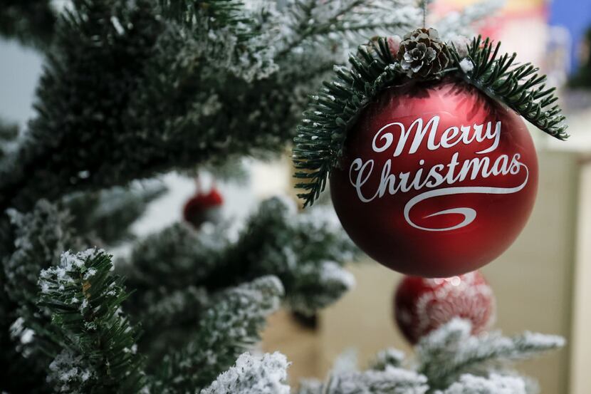A bauble emblazoned with Merry Christmas hangs from a Christmas tree on display inside an El...