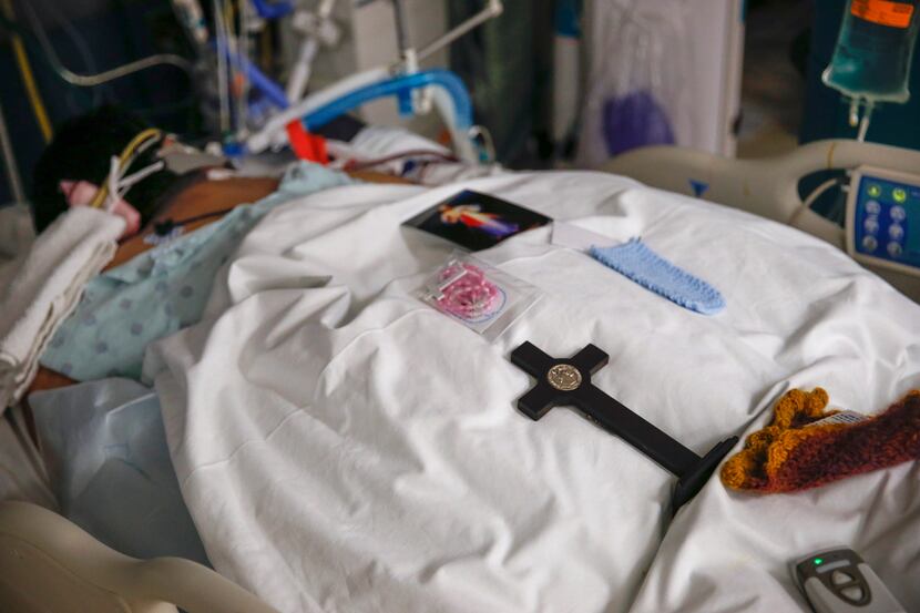 A cross, rosary and prayer card provided by a patient’s family rest on the person’s...