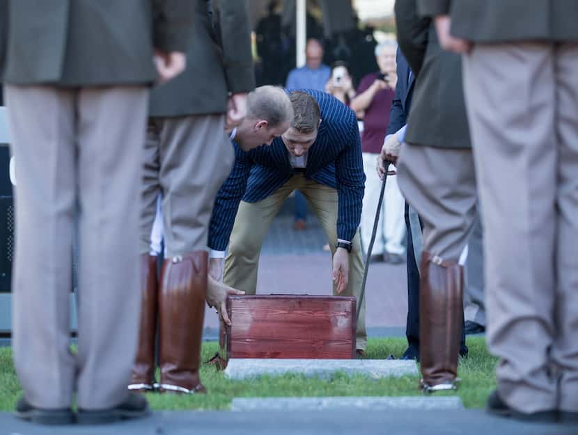 Former handlers of Reveille VIII Daylon Most (left) and Ian Moss work to lower the casket...