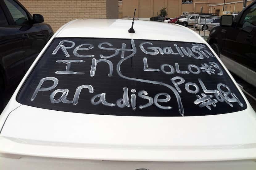 A car parked outside of Euless Trinity High School bears a painted tribute to three former...