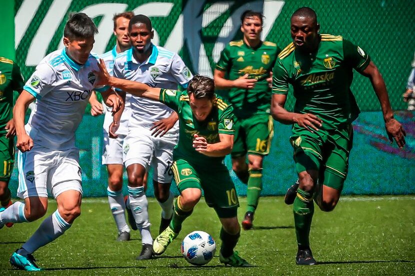 Portland Timbers midfielder Sebatian Blanco, center, tries to keep the ball against a...