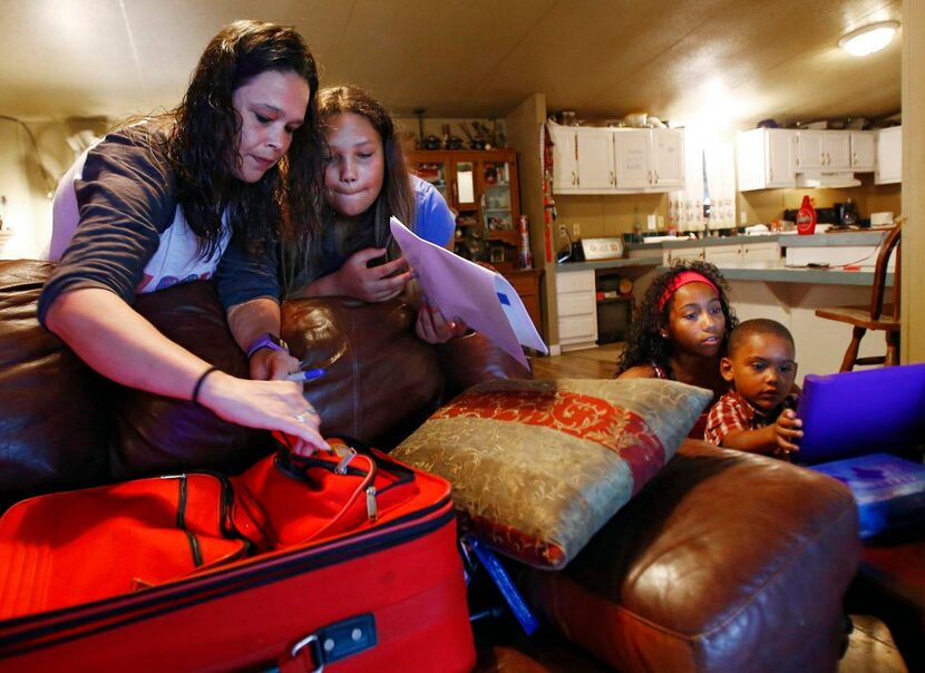 
Maleah Funk (second from left), and her mother Valorie Funk (left) pack her suitcase as...