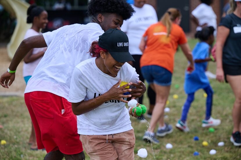 Kids have a water balloon fight wearing Live United hats and shirts from United Way