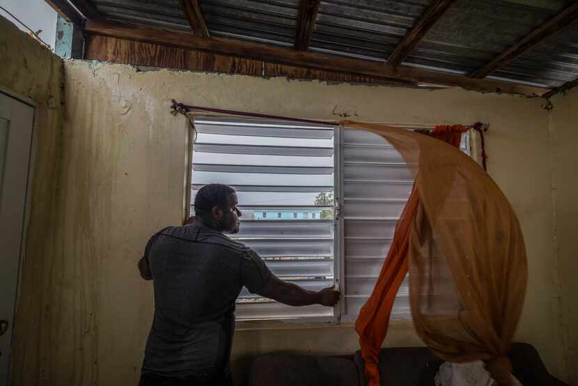 Nelson Cirino secures the windows of his home as the winds of Hurricane Fiona blow in Loiza,...